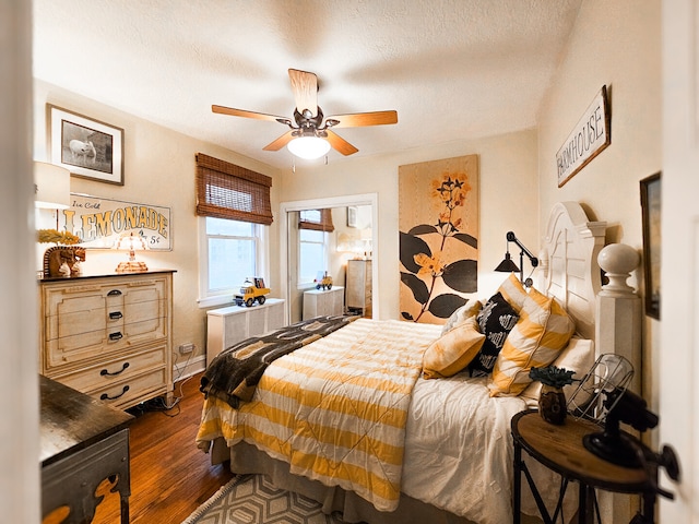 bedroom with ceiling fan, dark wood-type flooring, and a textured ceiling