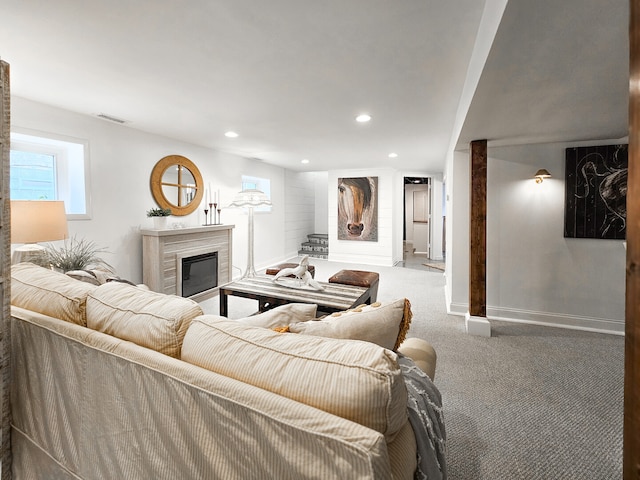 carpeted living area with a high end fireplace, visible vents, recessed lighting, and baseboards