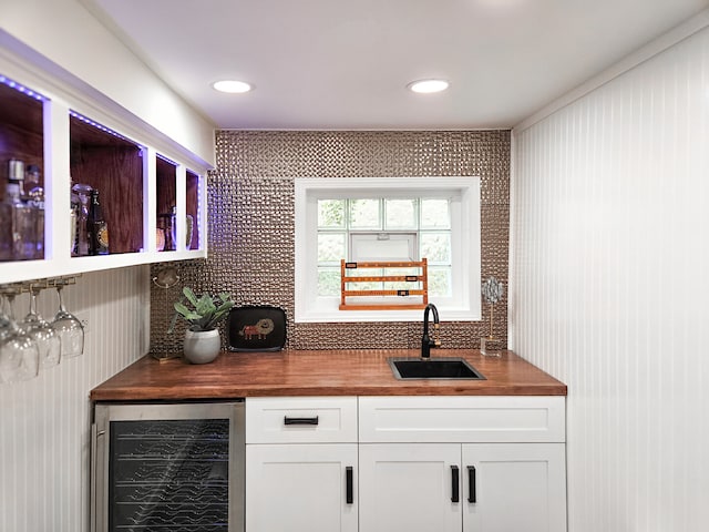 bar with wine cooler, bar area, tasteful backsplash, and a sink