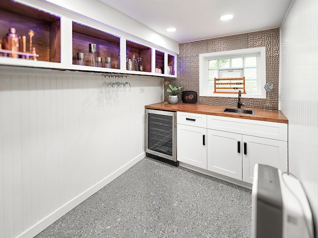 bar featuring a sink, light speckled floor, recessed lighting, wine cooler, and baseboards