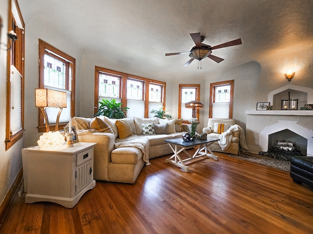 living room with hardwood / wood-style floors, a textured ceiling, ceiling fan, and a fireplace