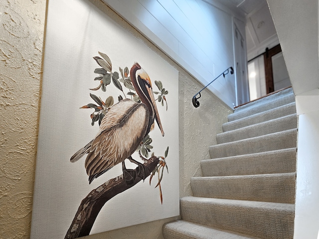 stairway featuring a barn door and a textured wall