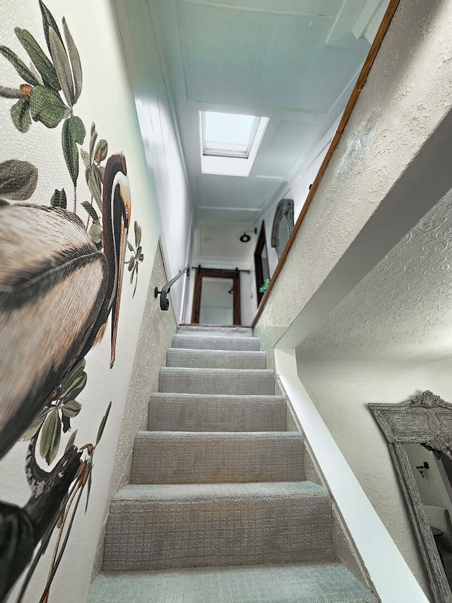 stairway with a skylight and a textured wall