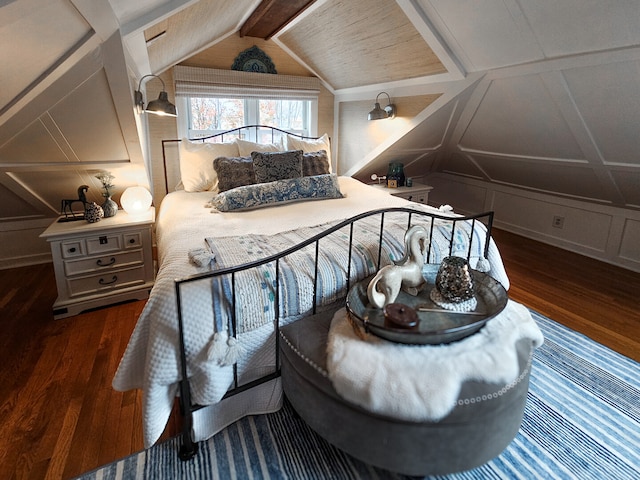 bedroom featuring wood finished floors, vaulted ceiling with beams, and a decorative wall