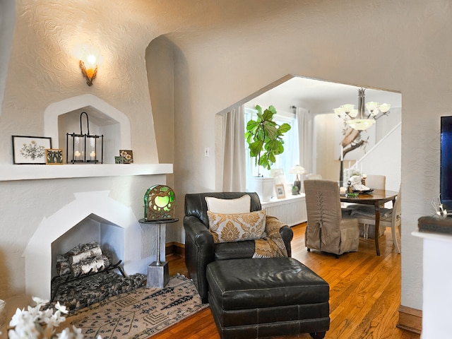 interior space with a chandelier, radiator, a textured wall, and wood finished floors