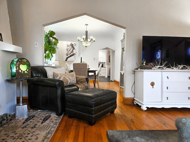 living room with baseboards, wood-type flooring, a notable chandelier, and arched walkways