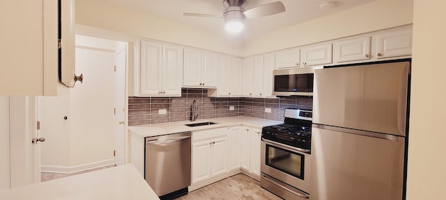 kitchen with a sink, tasteful backsplash, white cabinetry, appliances with stainless steel finishes, and light countertops