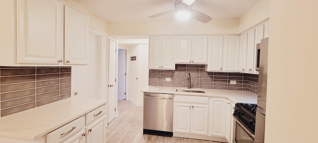 kitchen with range with gas cooktop, light countertops, stainless steel dishwasher, a ceiling fan, and a sink