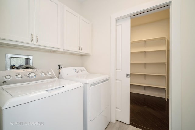 clothes washing area with cabinet space, light wood-style flooring, and washing machine and clothes dryer