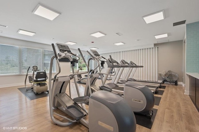 gym with a wealth of natural light, light wood-type flooring, and baseboards