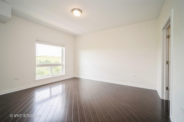 spare room with baseboards and dark wood-style floors