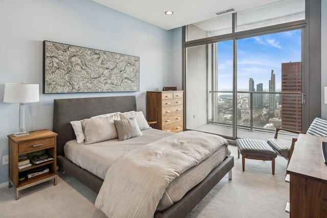 bedroom with visible vents, floor to ceiling windows, light carpet, recessed lighting, and a view of city