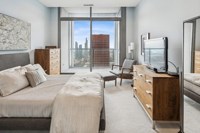 bedroom featuring a wall of windows, visible vents, and light colored carpet