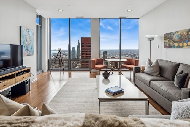 living area with a wall of windows, a view of city, wood finished floors, and recessed lighting