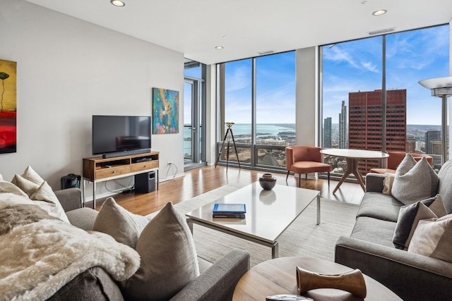 living area featuring visible vents, recessed lighting, a wall of windows, and wood finished floors