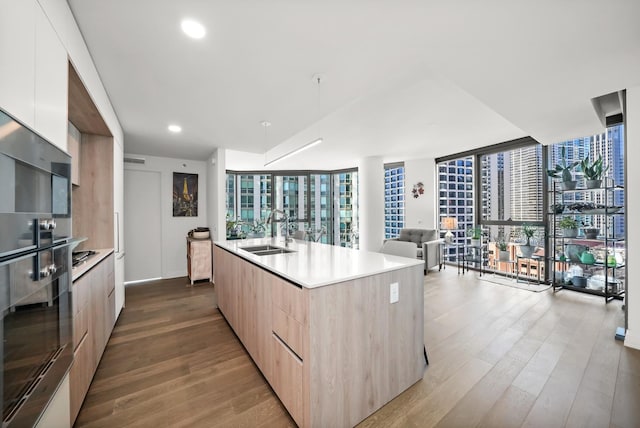 kitchen featuring a sink, modern cabinets, wood finished floors, and light brown cabinets