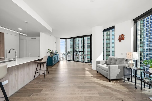 living room with plenty of natural light, a wall of windows, visible vents, and wood finished floors