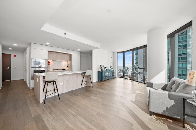 living room featuring recessed lighting, light wood-style flooring, and a wall of windows