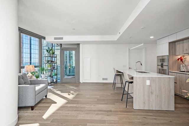 kitchen featuring visible vents, a kitchen bar, modern cabinets, light wood-style flooring, and a sink