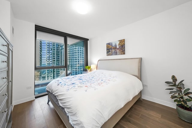 bedroom with a wall of windows, baseboards, and dark wood-style flooring