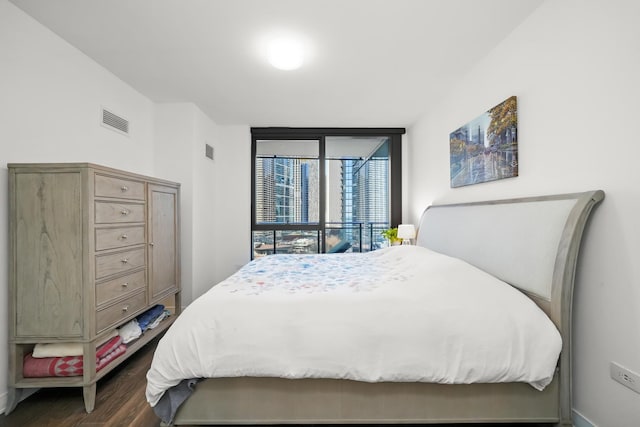 bedroom with visible vents, dark wood-style floors, and expansive windows