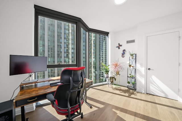 office area featuring a wall of windows, visible vents, and wood finished floors