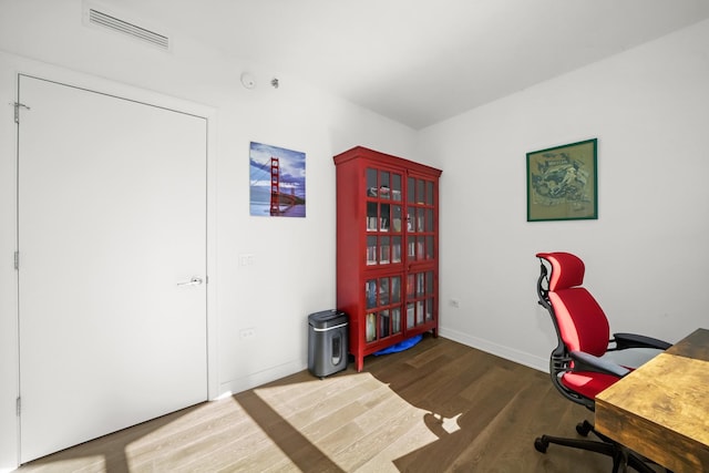 office space with wood finished floors, visible vents, and baseboards