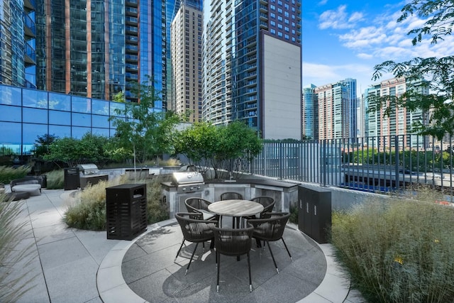 view of patio featuring a view of city, a grill, exterior kitchen, and fence