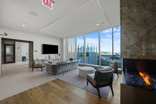 living room with a wall of windows, a large fireplace, recessed lighting, and light wood finished floors