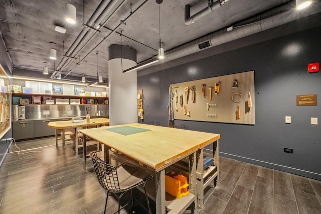 dining space with visible vents, baseboards, a workshop area, and wood finished floors