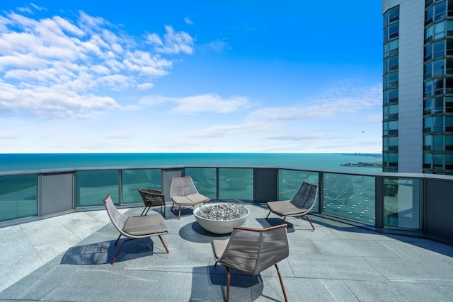 balcony featuring a water view and an outdoor fire pit