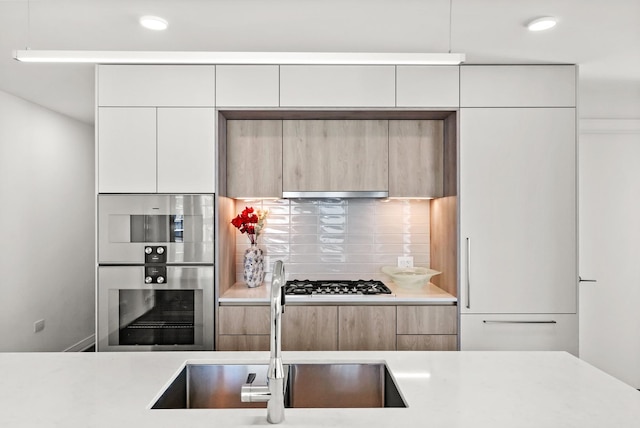 kitchen with modern cabinets, gas cooktop, light countertops, and a sink