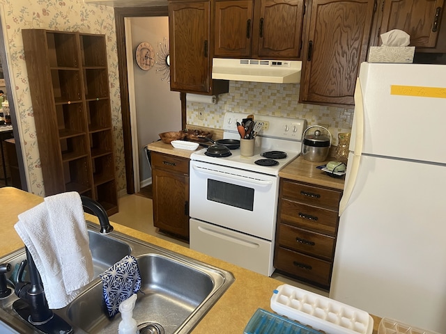 kitchen with white appliances, light countertops, under cabinet range hood, and a sink