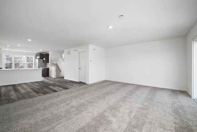 unfurnished living room featuring dark colored carpet, baseboards, and recessed lighting