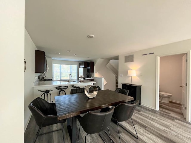 dining space with stairs, baseboards, visible vents, and light wood finished floors