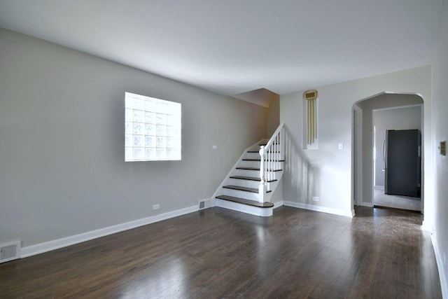 interior space featuring visible vents, arched walkways, dark wood-type flooring, and baseboards