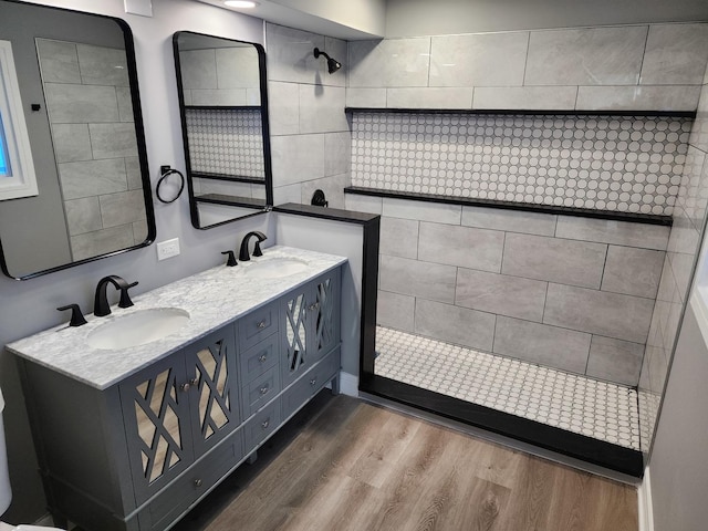 bathroom featuring a sink, wood finished floors, double vanity, and a walk in shower