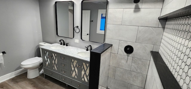 bathroom featuring toilet, wood finished floors, baseboards, and a sink