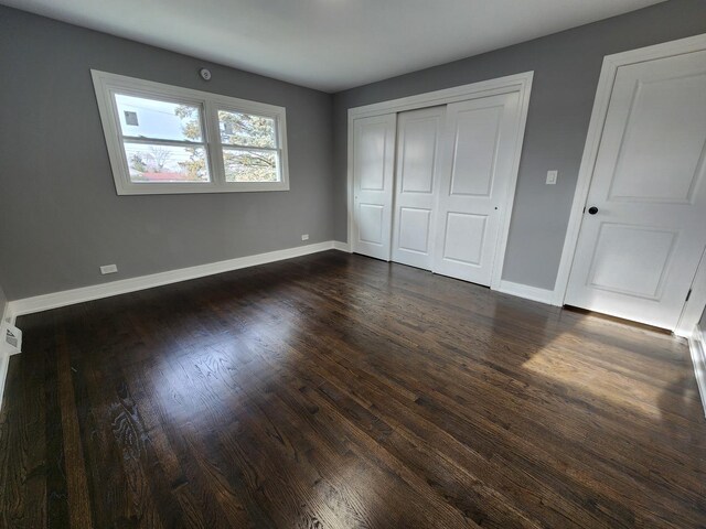 unfurnished bedroom featuring a closet, baseboards, and dark wood-style floors