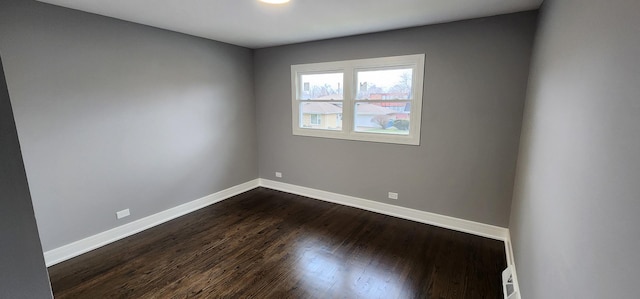 empty room featuring dark wood-style floors and baseboards