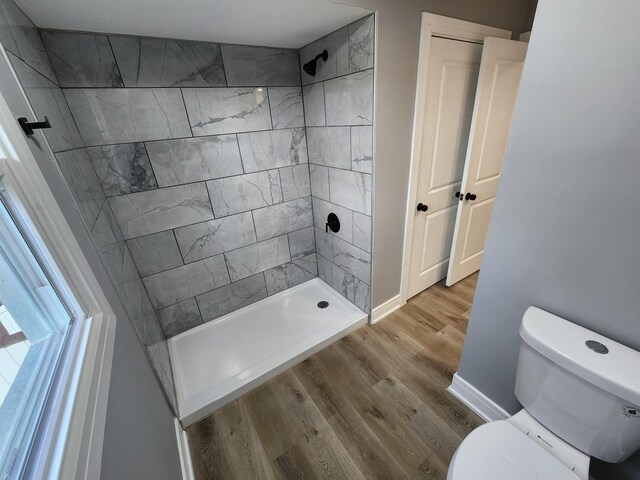 bathroom with a stall shower, toilet, baseboards, and wood finished floors