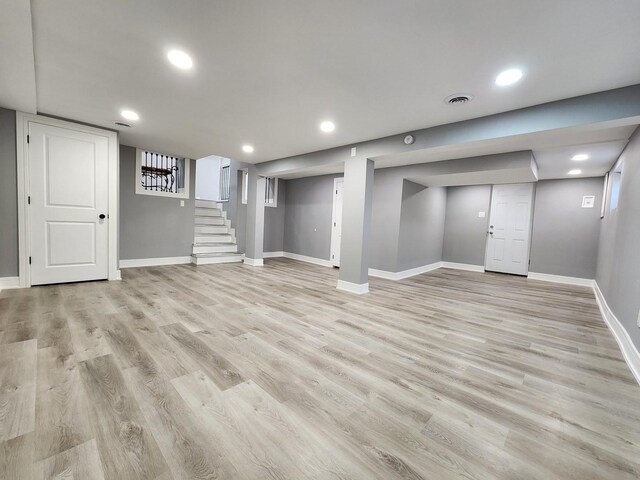 finished below grade area with stairs, recessed lighting, light wood-style floors, and visible vents