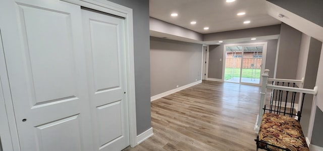 hallway featuring light wood-style flooring, recessed lighting, and baseboards