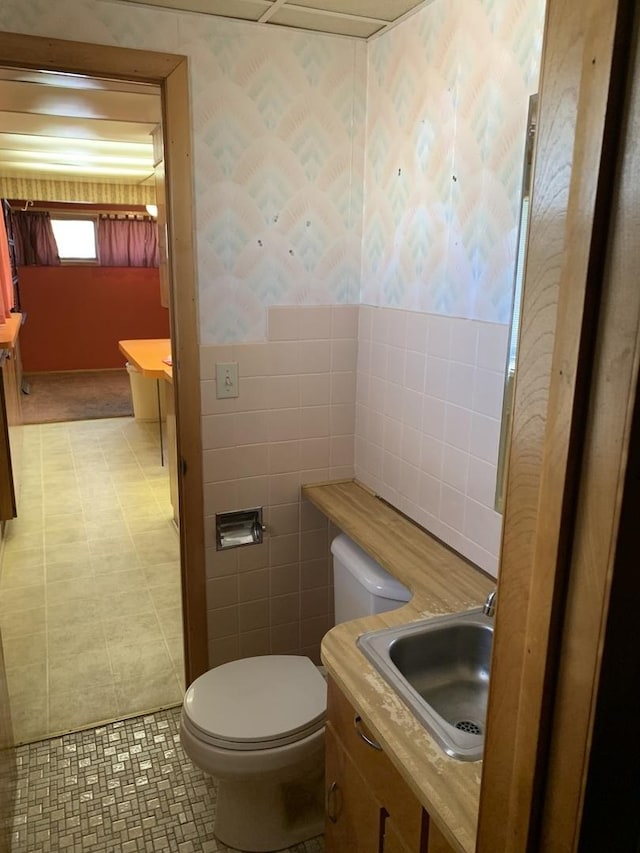 half bathroom featuring toilet, tile walls, and vanity