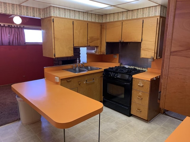 kitchen with black range with gas cooktop, wallpapered walls, light countertops, and a sink