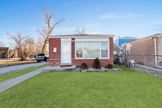 view of front of property with aphalt driveway, brick siding, a front yard, and fence