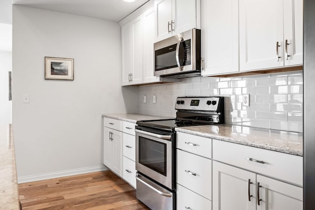 kitchen featuring tasteful backsplash, baseboards, stainless steel appliances, light wood-style floors, and white cabinetry