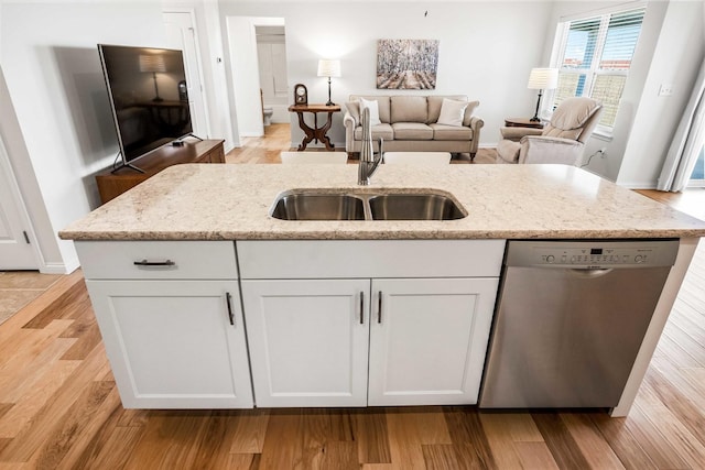 kitchen featuring light stone counters, a sink, white cabinets, dishwasher, and light wood-type flooring