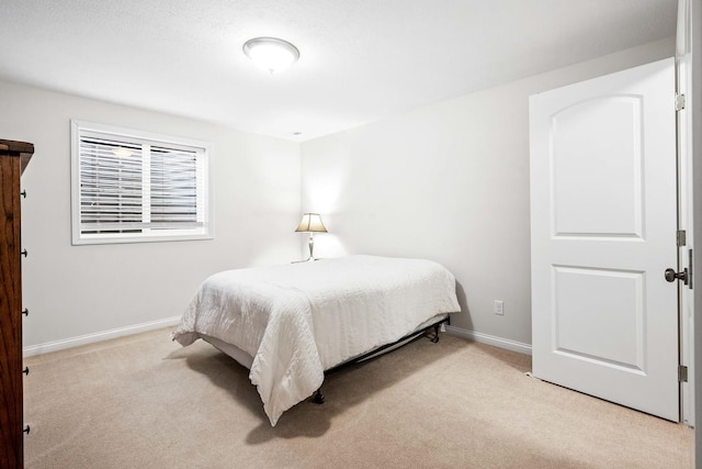 bedroom with light colored carpet and baseboards