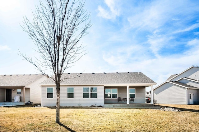 back of property with a lawn and roof with shingles